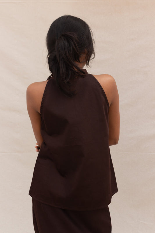 Woman wearing a brown halter top and pants against a beige background