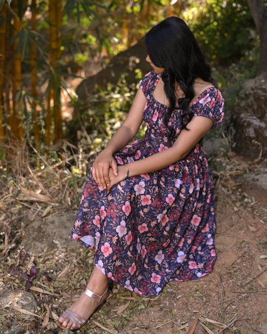 Woman in a floral dress sitting in a forest