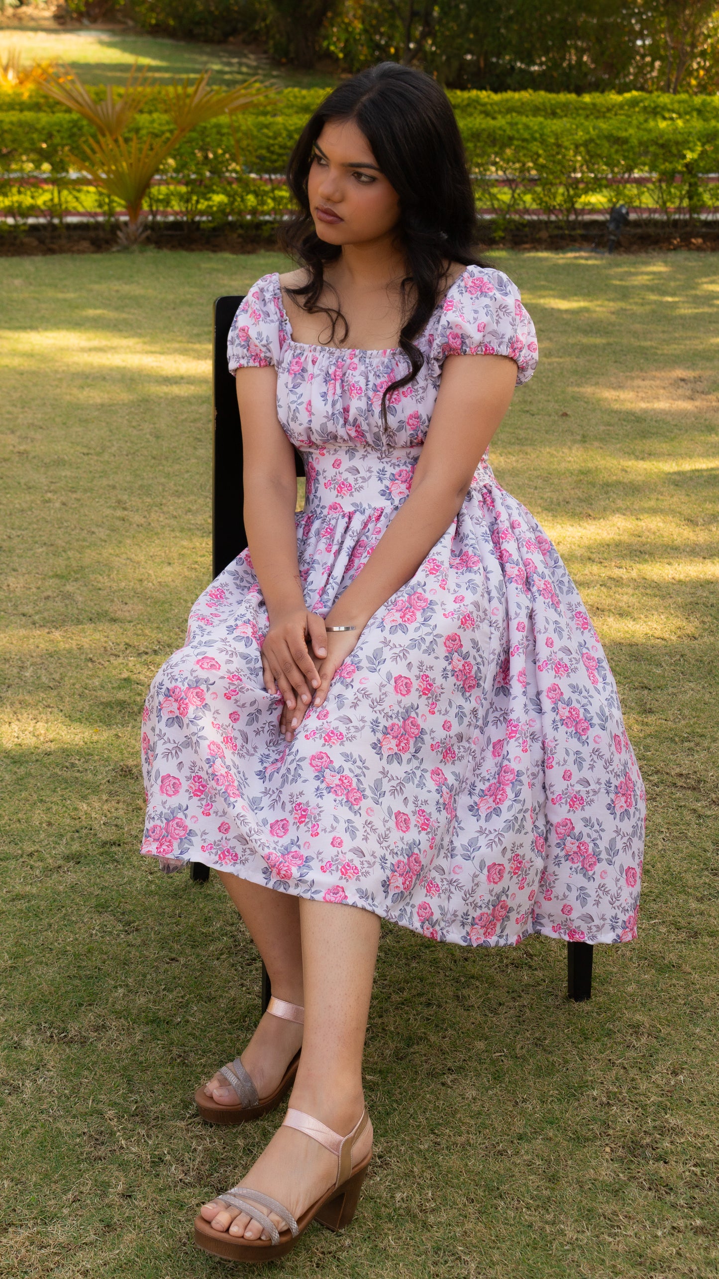 Woman in a floral dress sitting on grass