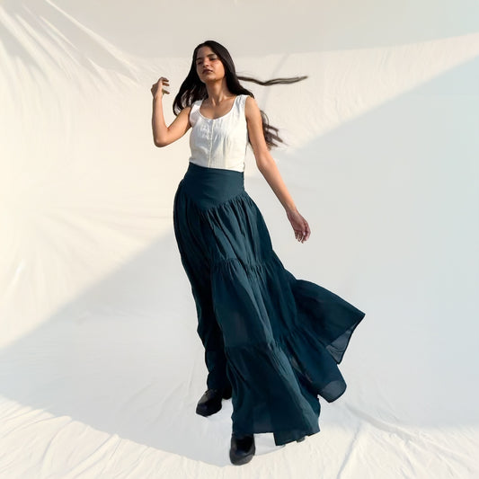 Woman wearing a white top and dark green skirt against a white background