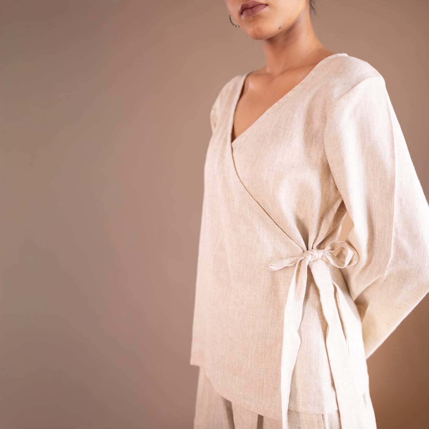 Beige outfit with a tie detail on a plain background