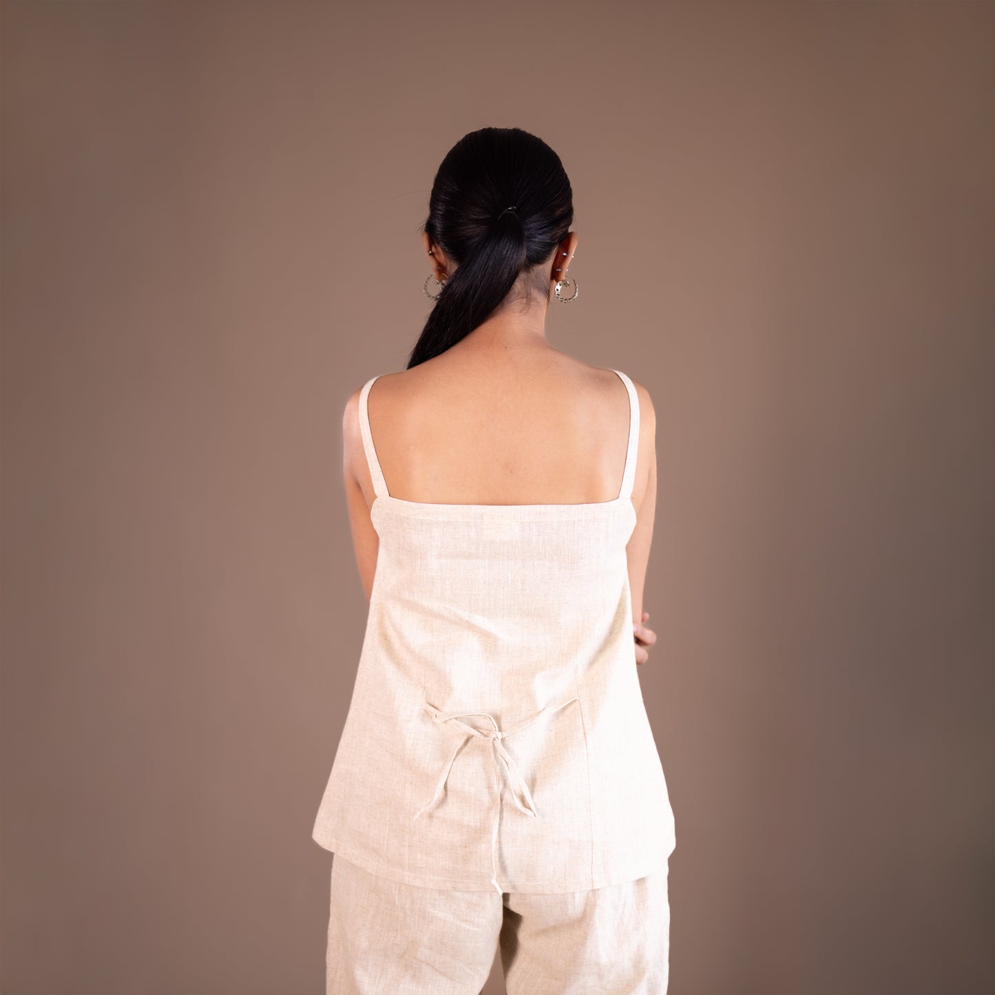 Woman wearing a light-colored outfit against a plain background