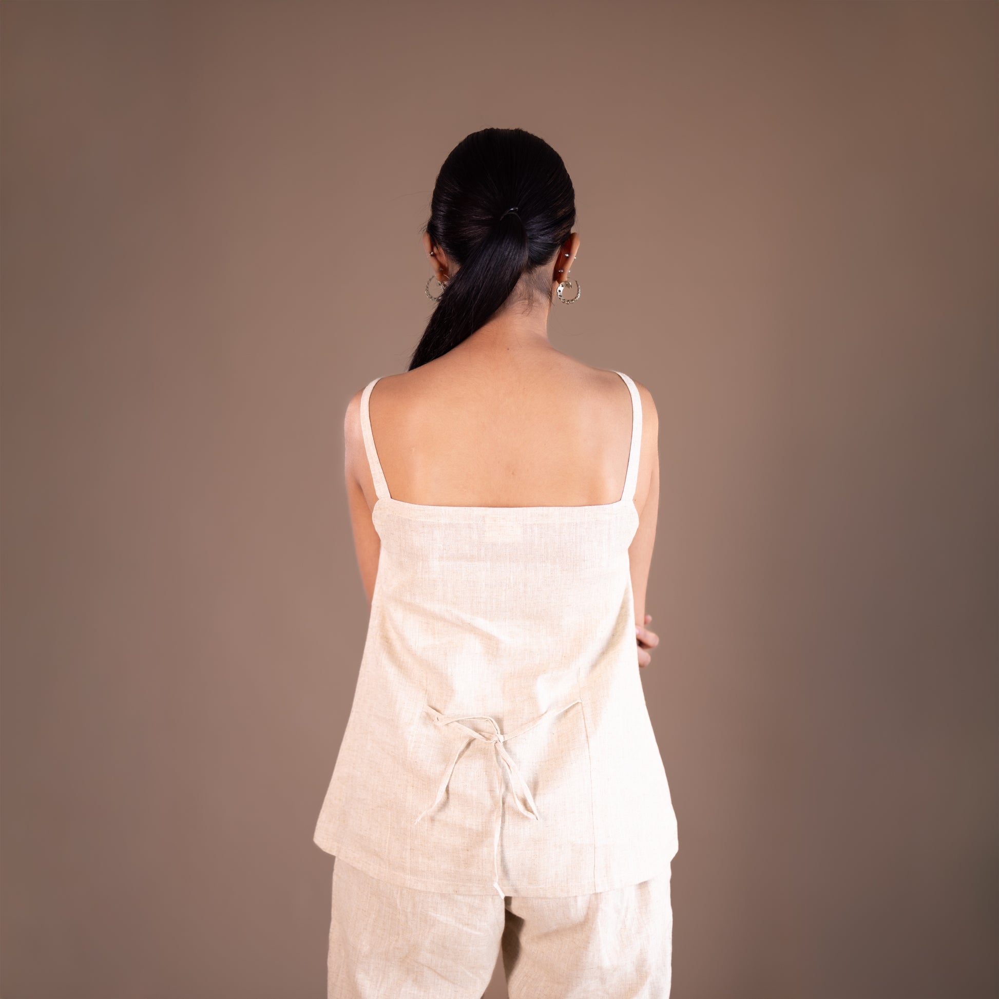 Woman wearing a light-colored outfit against a plain background