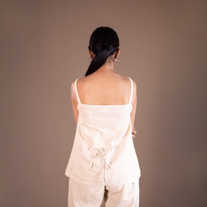 Woman wearing a light-colored outfit against a plain background