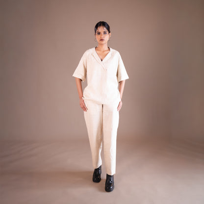Woman wearing a beige outfit against a brown background