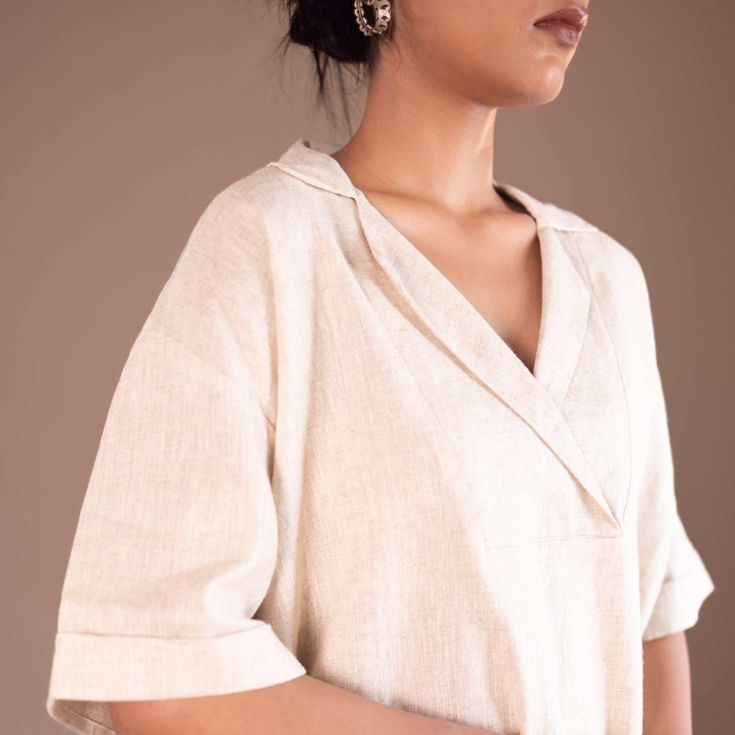 Woman wearing a light-colored blouse against a neutral background