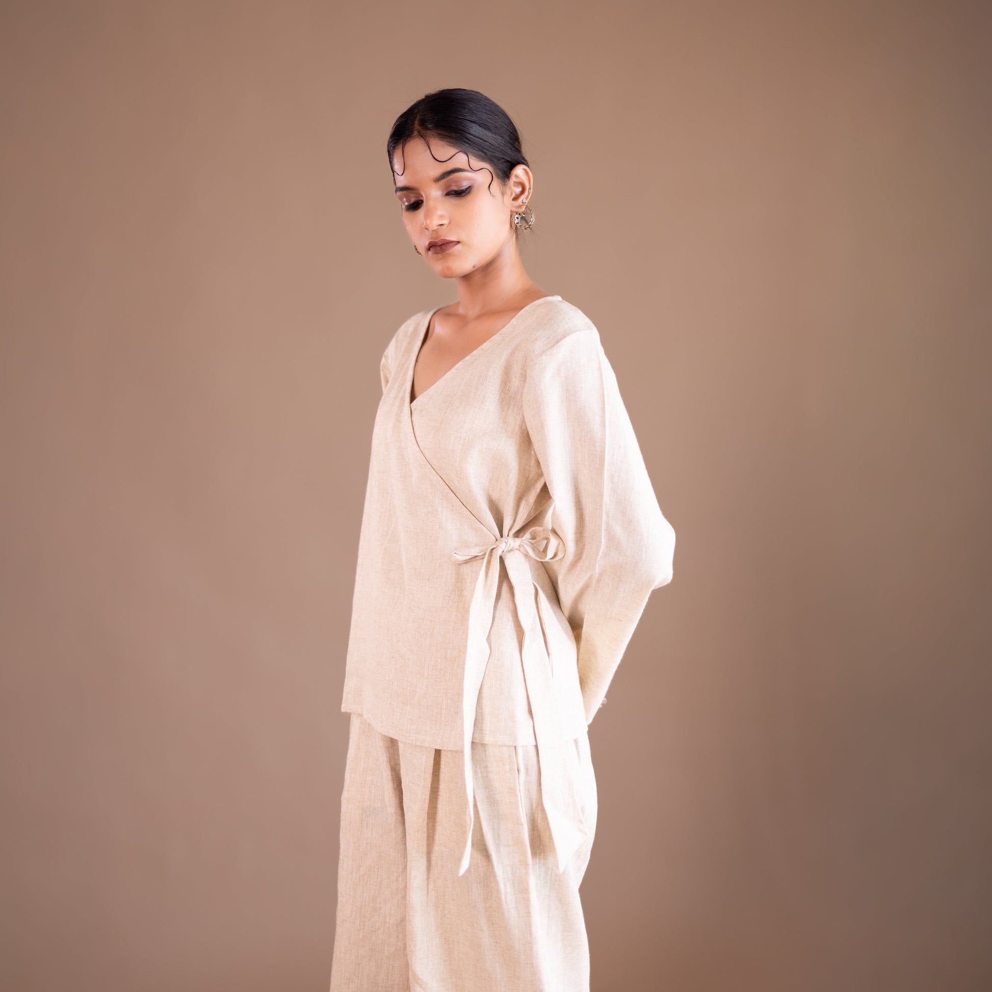 Woman wearing a beige outfit against a brown background