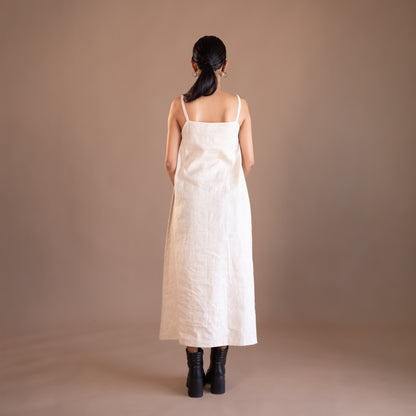 Woman wearing a beige dress standing against a brown background