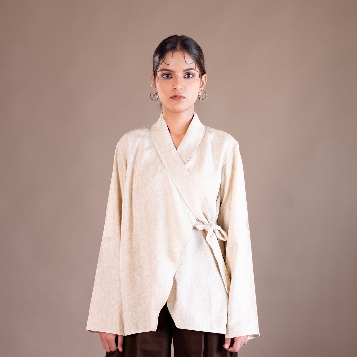 Woman wearing a beige kimono-style top against a brown background