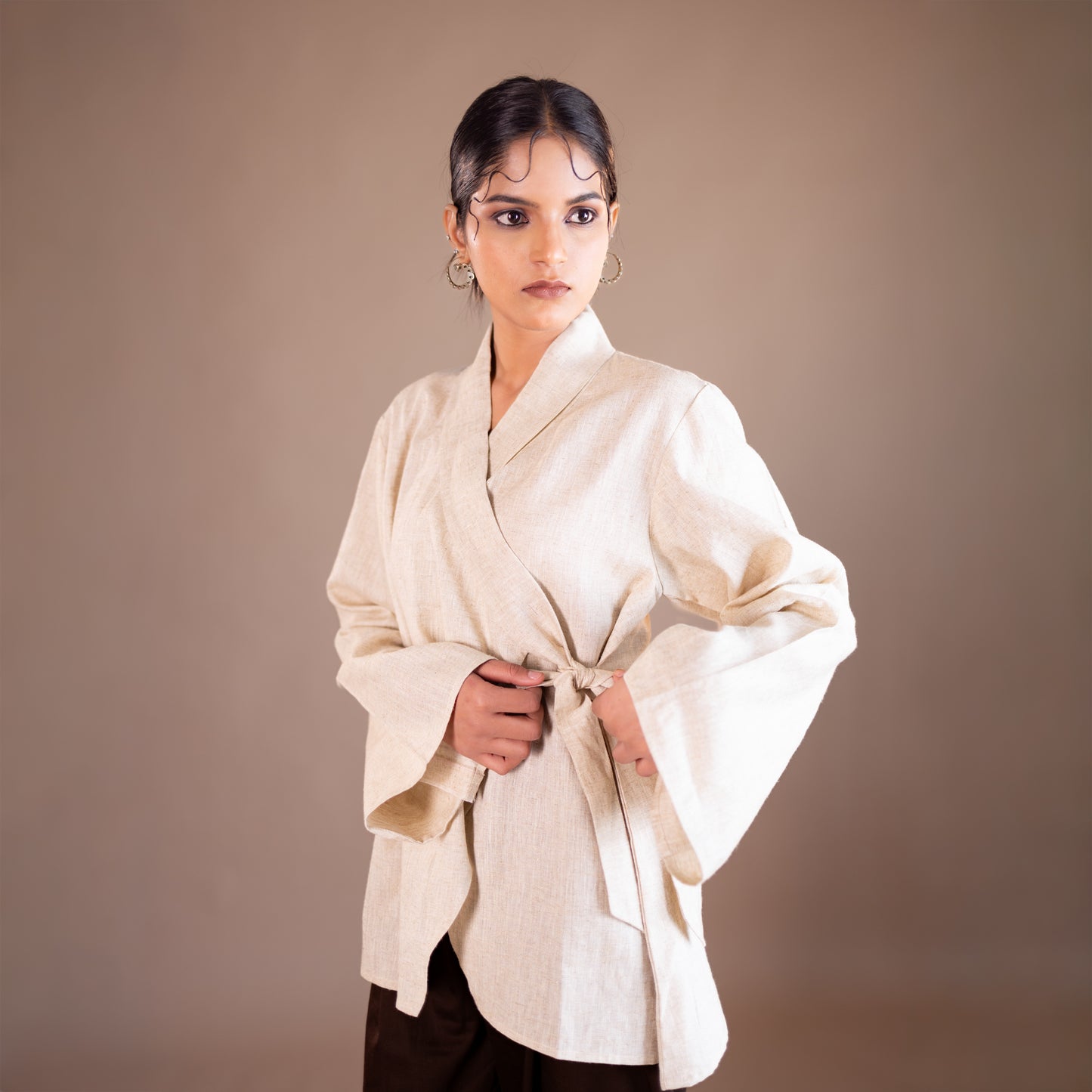 Woman wearing a white kimono-style garment against a brown background