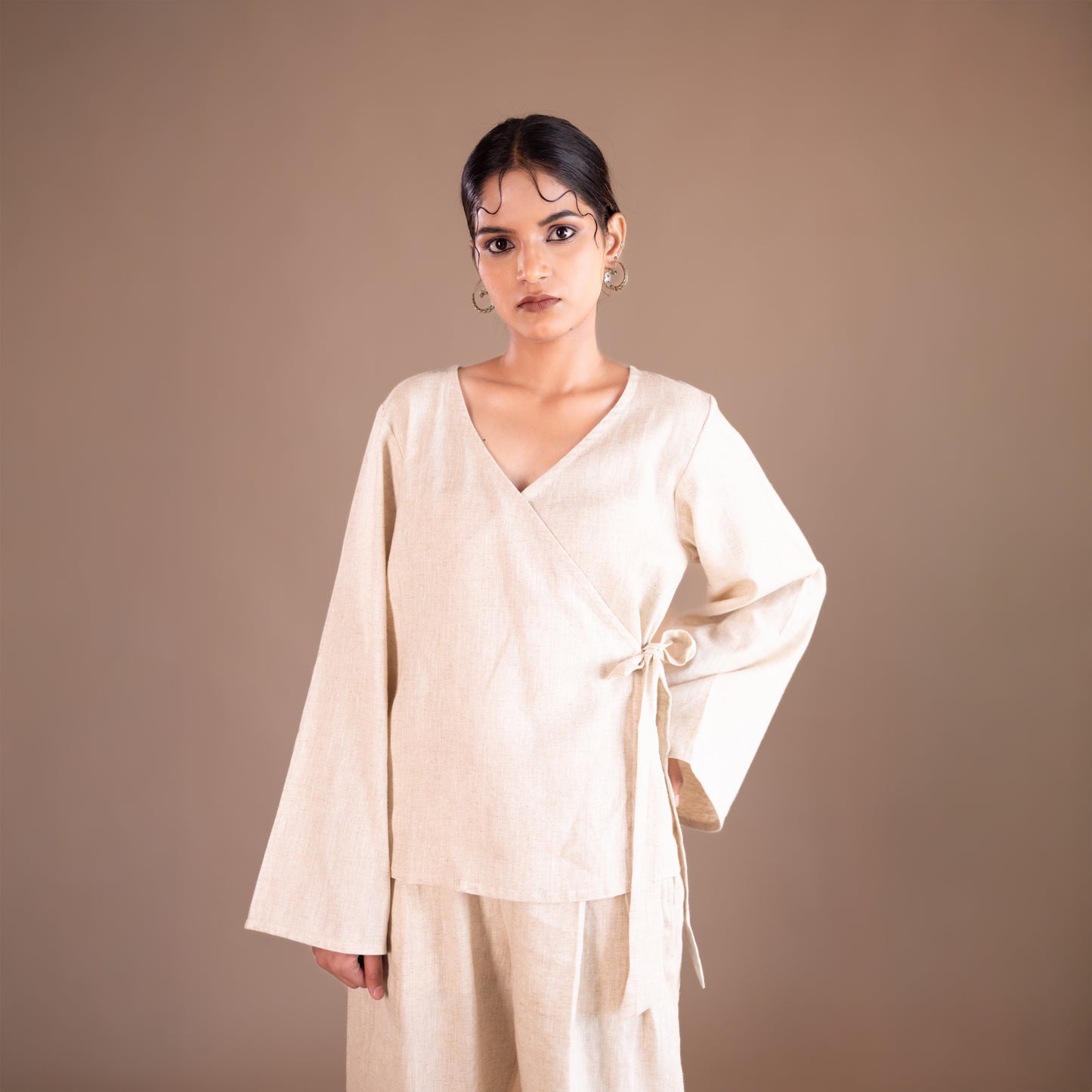Woman wearing a beige outfit against a brown background
