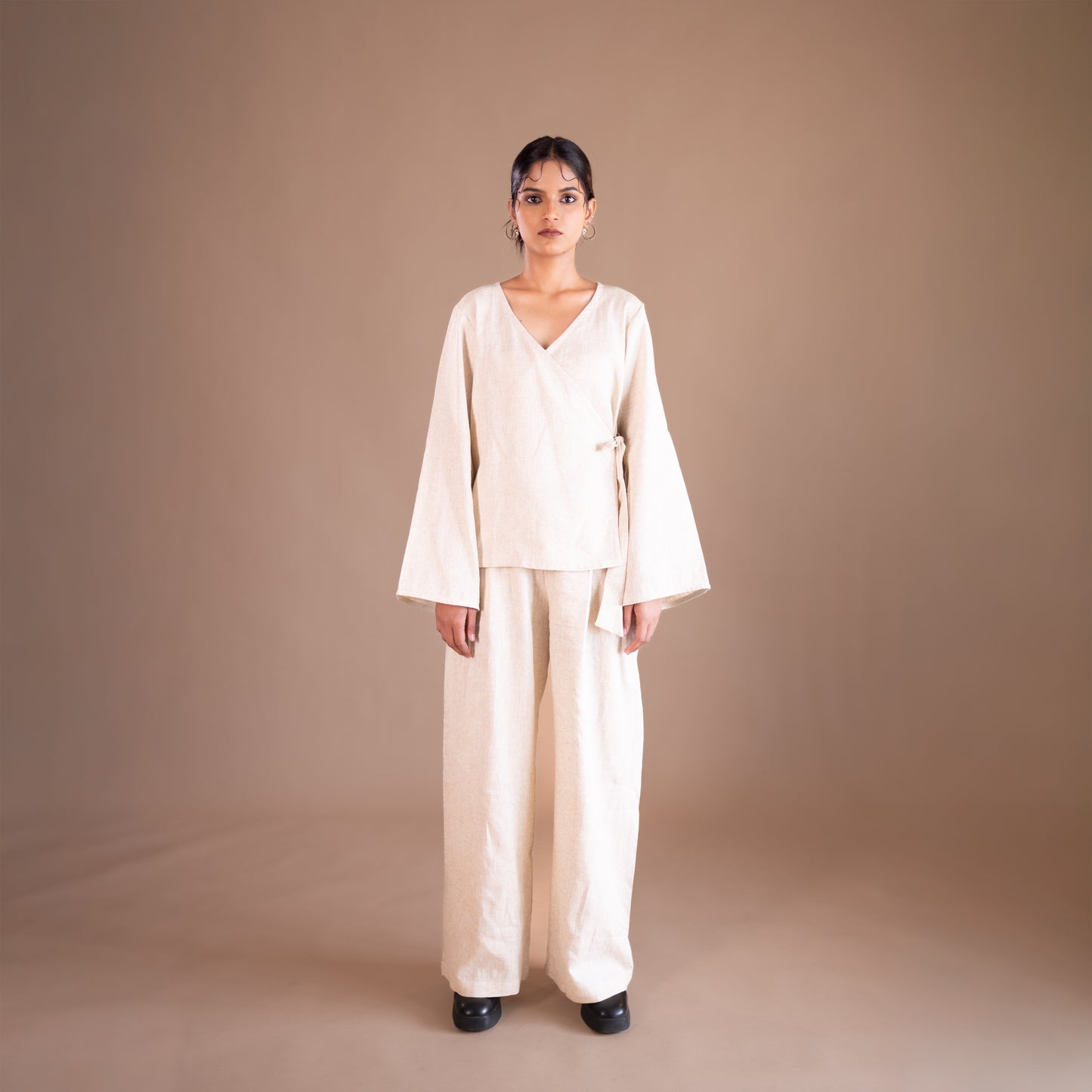 Woman wearing a cream-colored outfit against a brown background