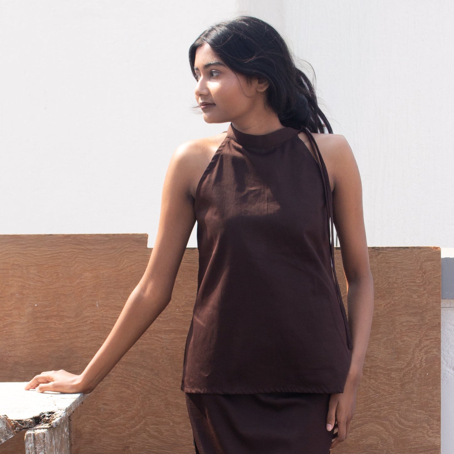 Woman wearing a brown sleeveless top and skirt against a neutral background