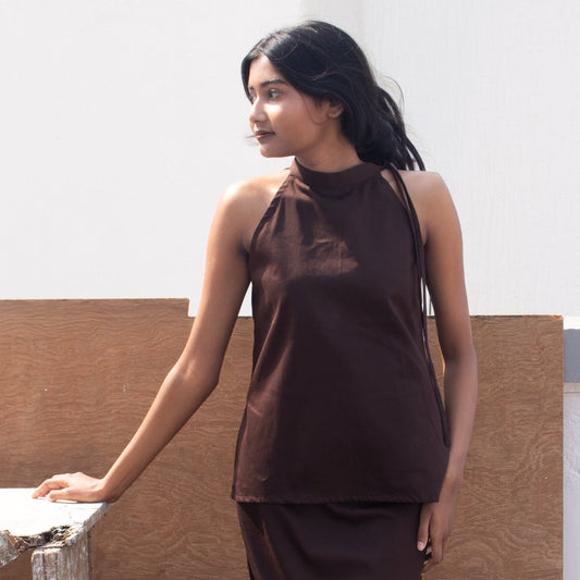 Woman wearing a brown sleeveless top and skirt against a neutral background