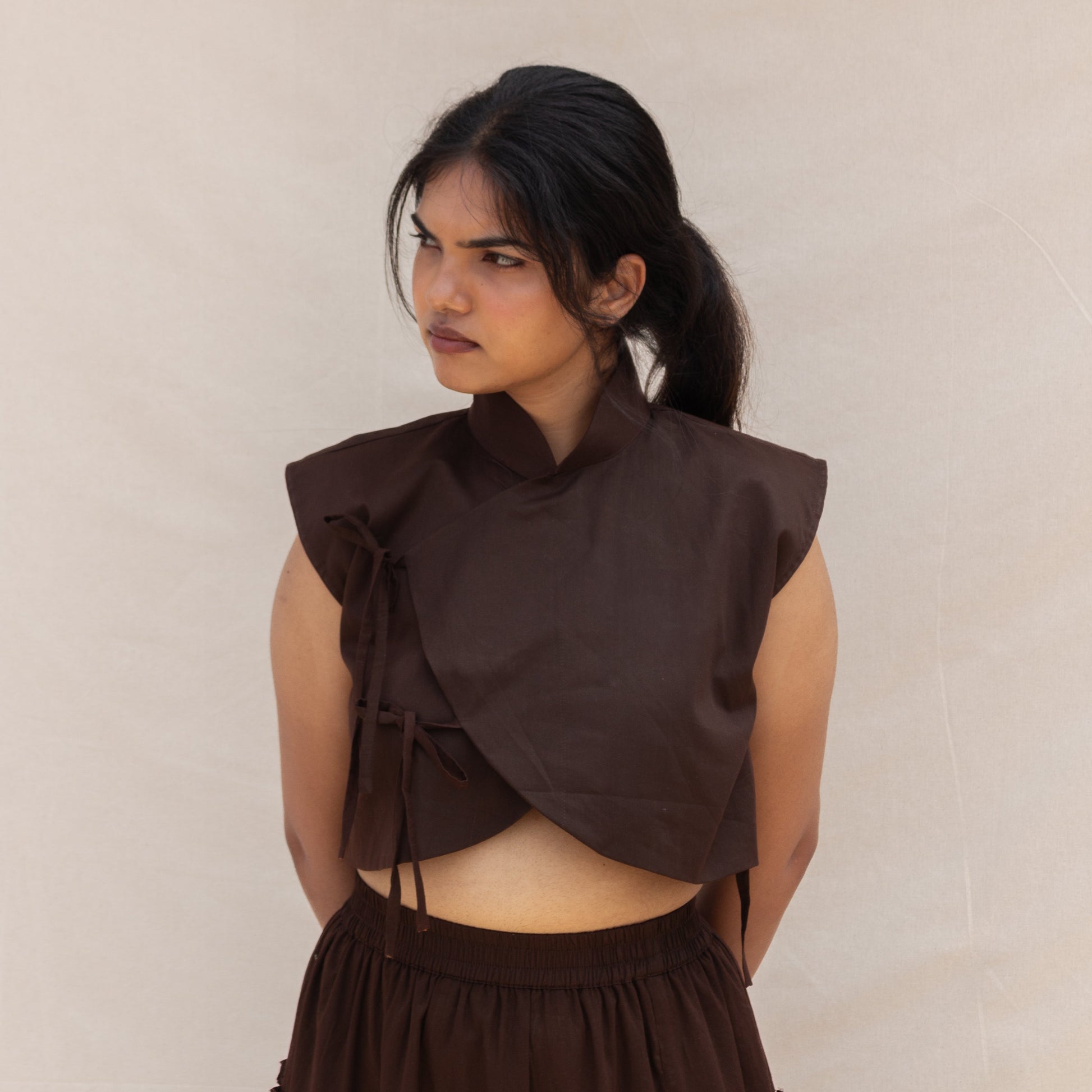 Woman wearing a brown dress with a ruffled top against a plain background