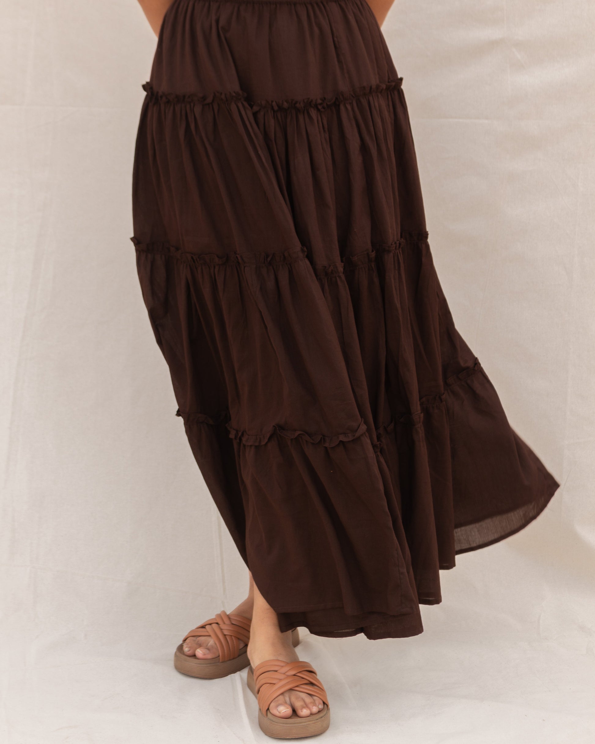 Brown tiered maxi skirt worn by a person on a white background
