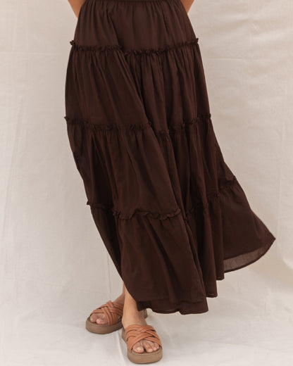 Brown tiered maxi skirt worn by a person on a white background