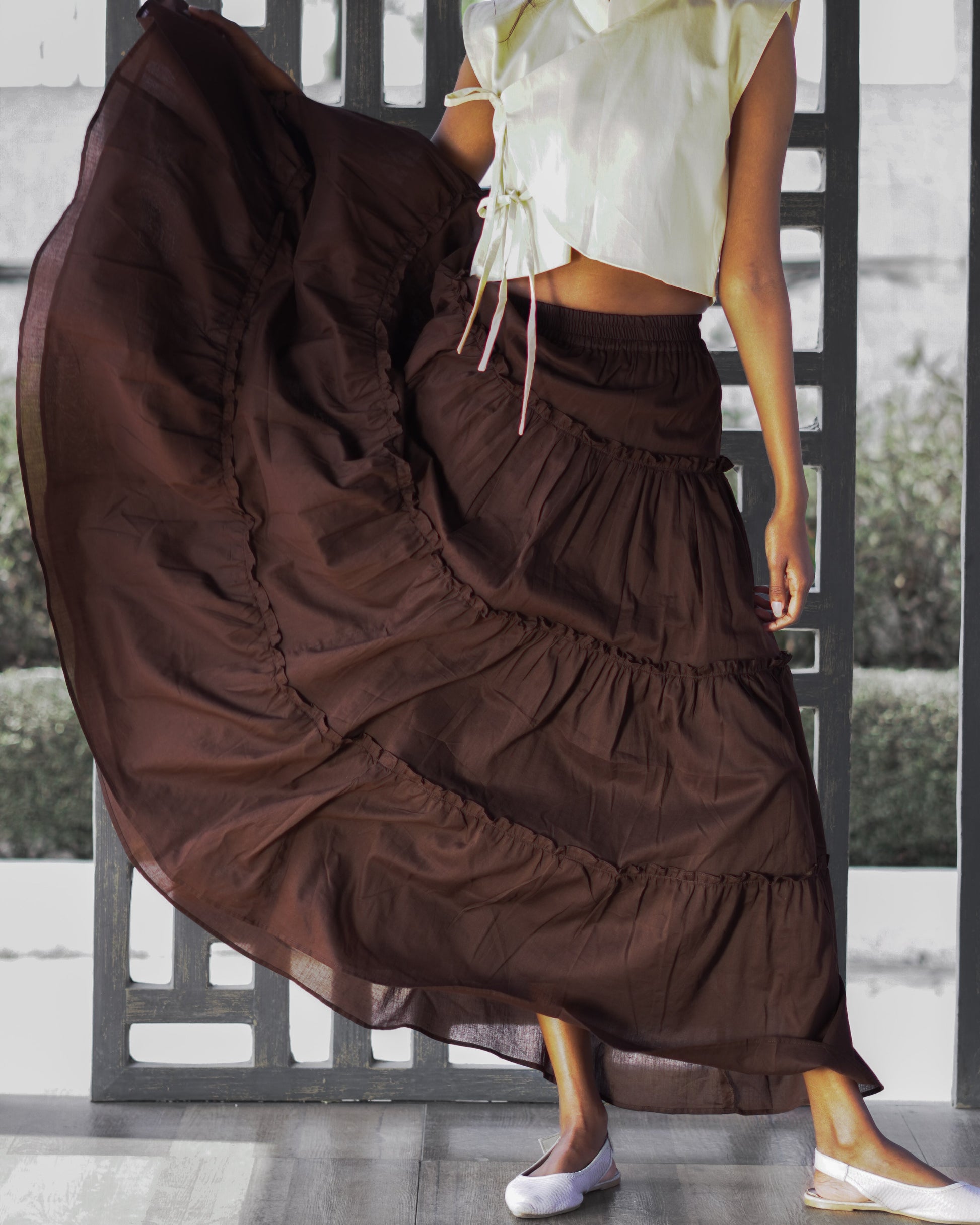 Person wearing a long brown layered skirt with a white top