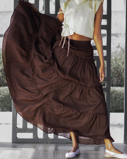 Person wearing a long brown layered skirt with a white top