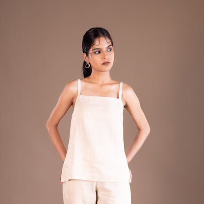 Woman wearing a beige top and pants against a brown background