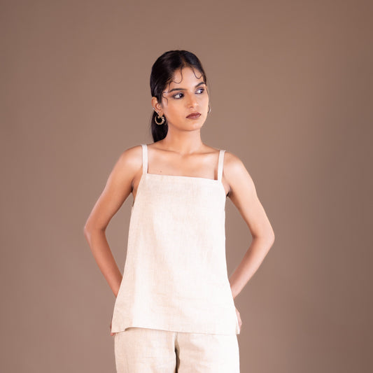 Woman wearing a beige top and pants against a brown background