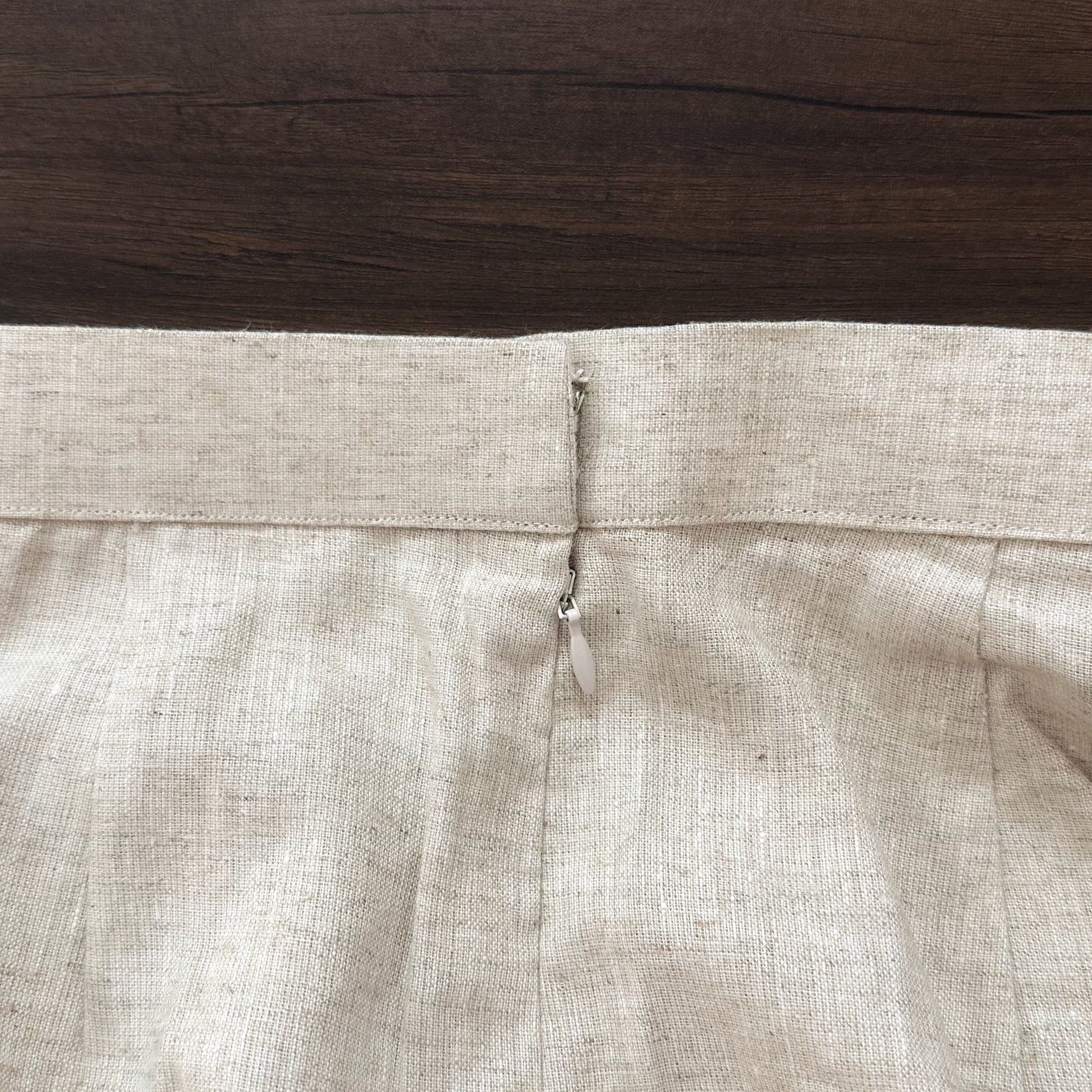 Close-up of beige trouser with zipper on a wooden surface
