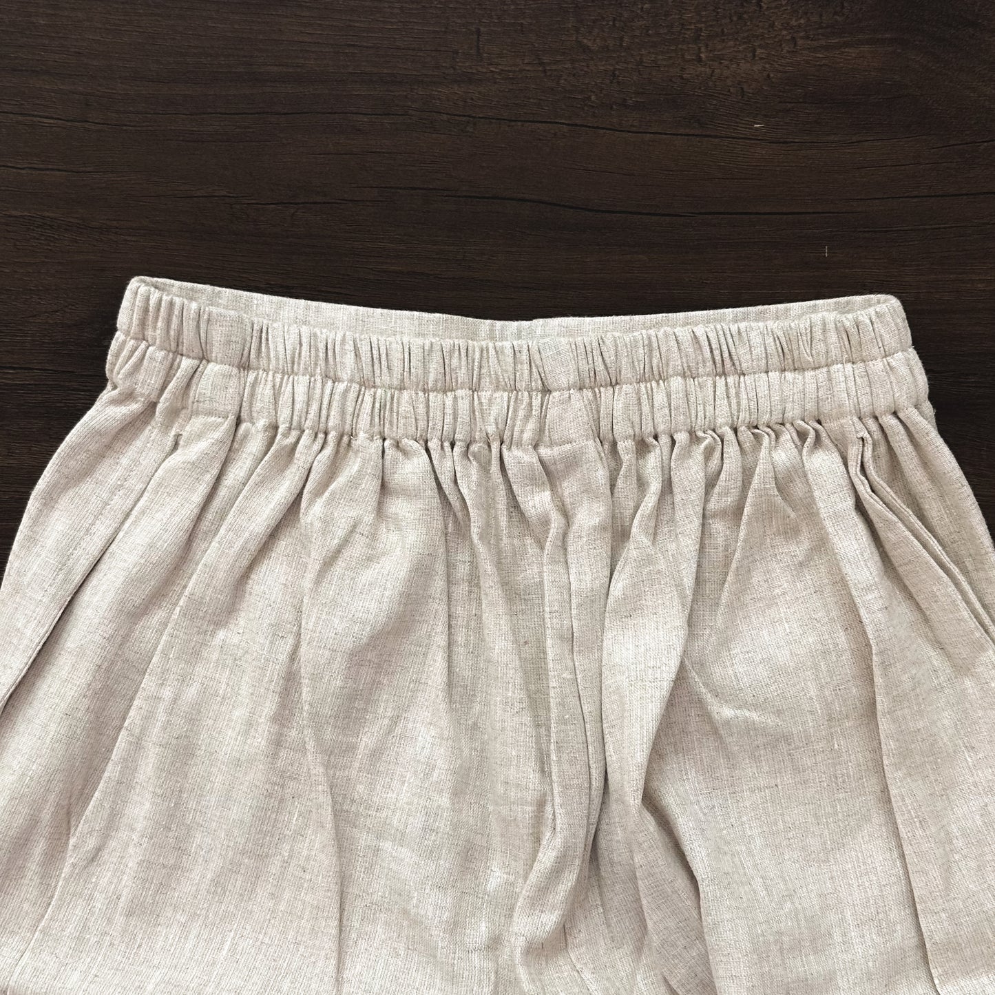 Beige linen cropped pants on a wooden surface
