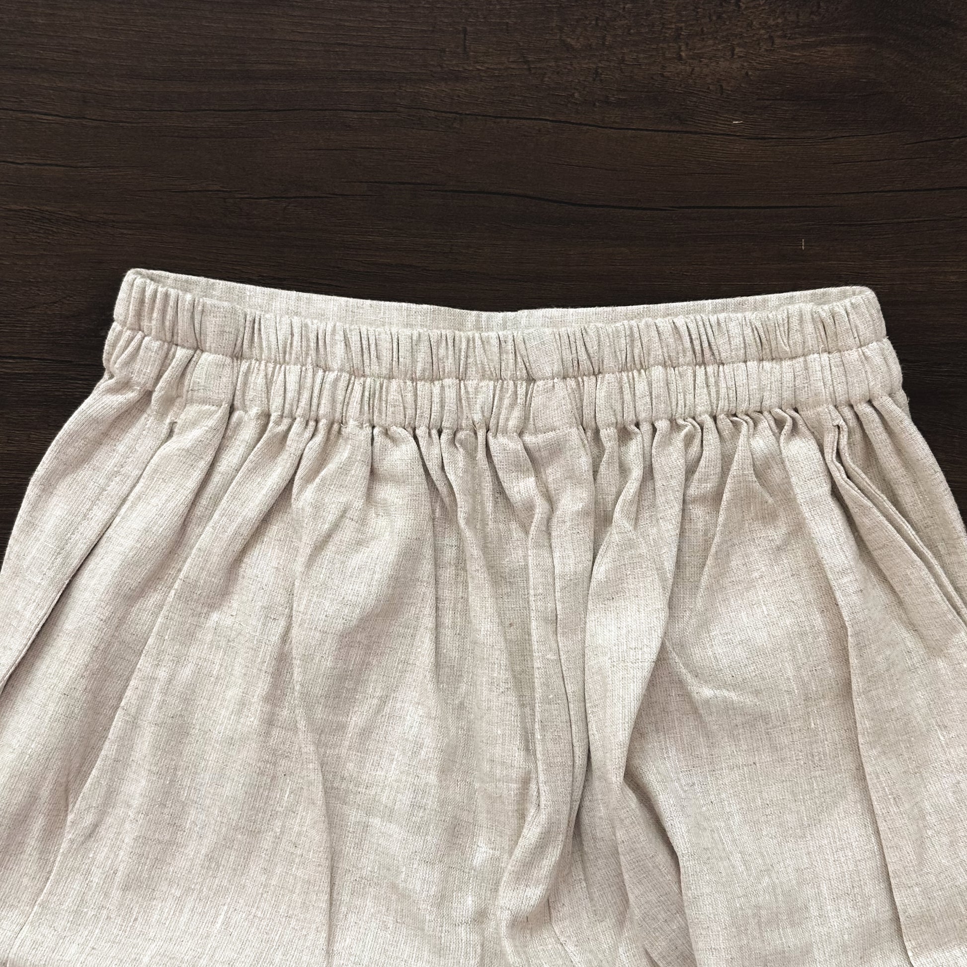 Beige linen cropped pants on a wooden surface