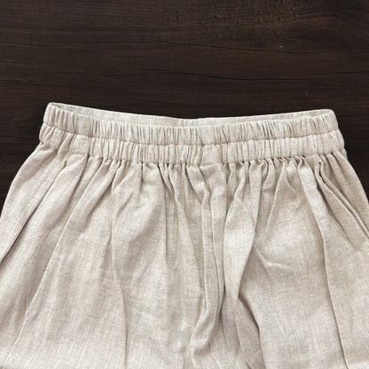 Beige linen cropped pants on a wooden surface