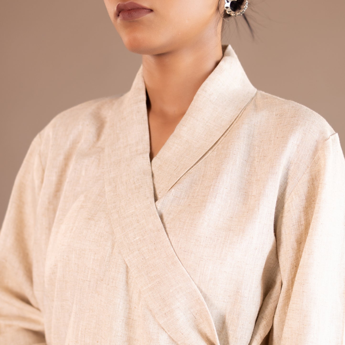Close-up of a person wearing a beige robe against a neutral background