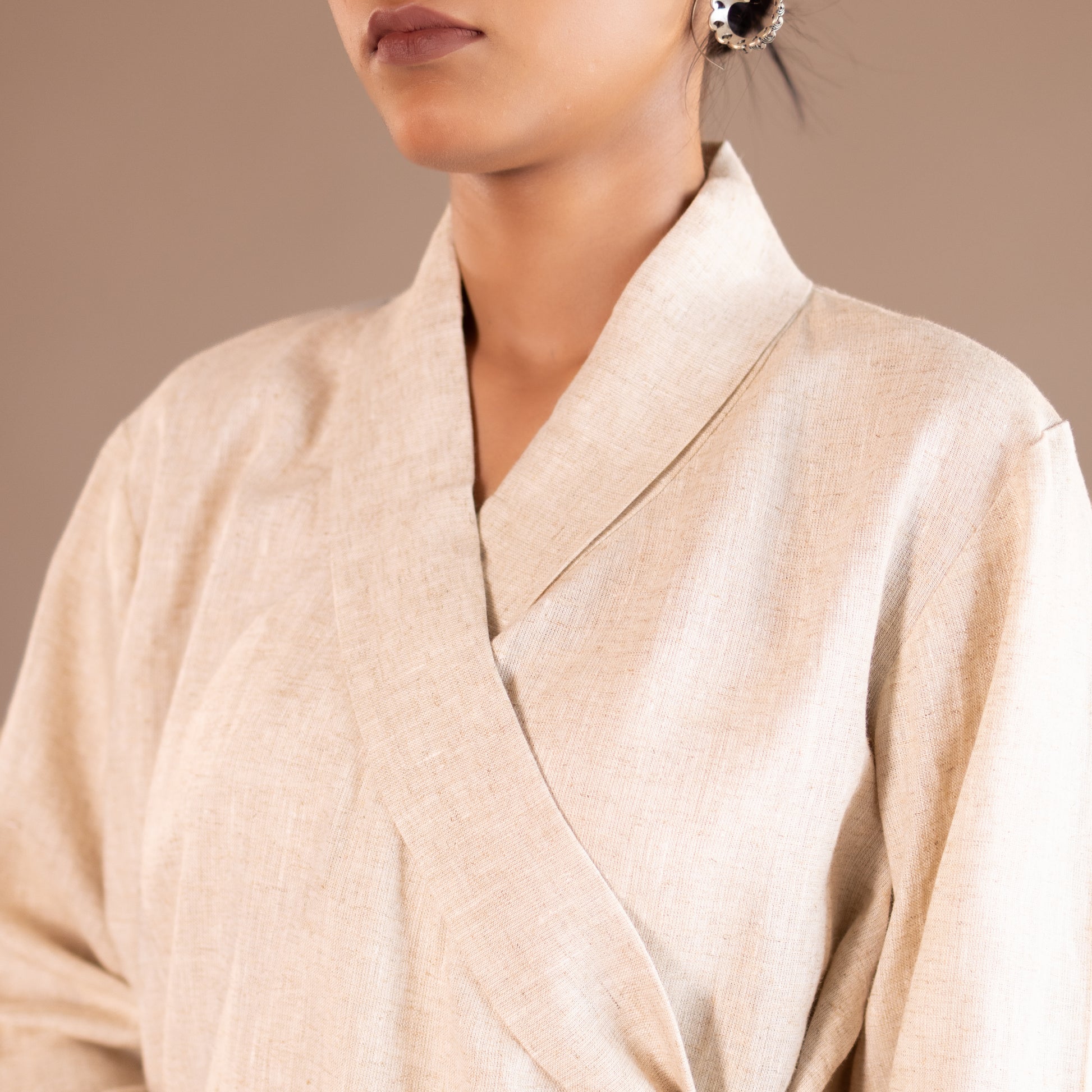 Close-up of a person wearing a beige robe against a neutral background