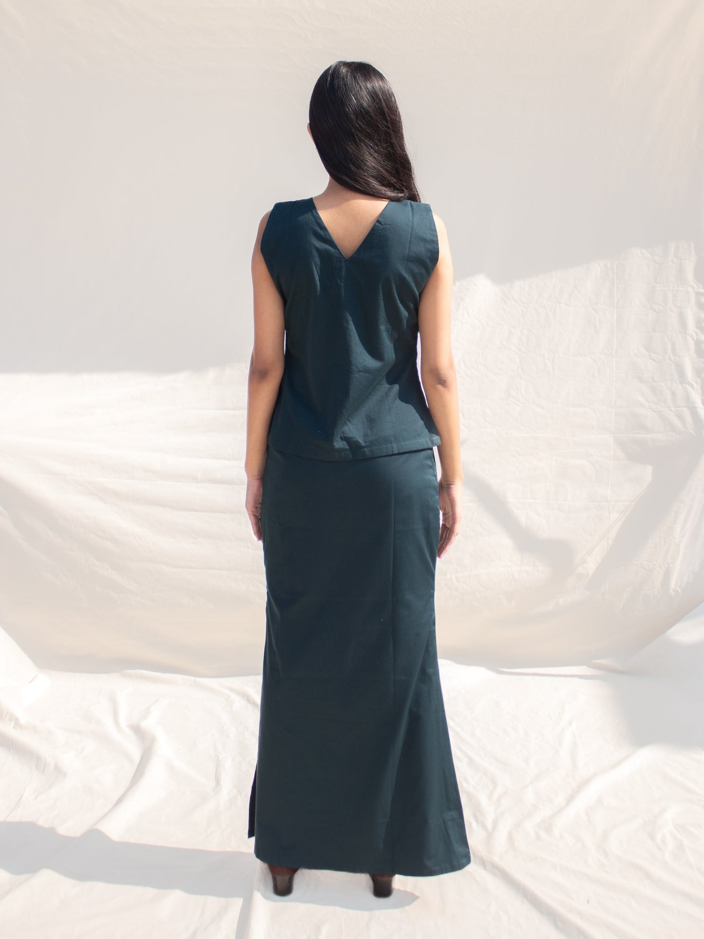 Woman wearing a dark green sleeveless dress against a white background