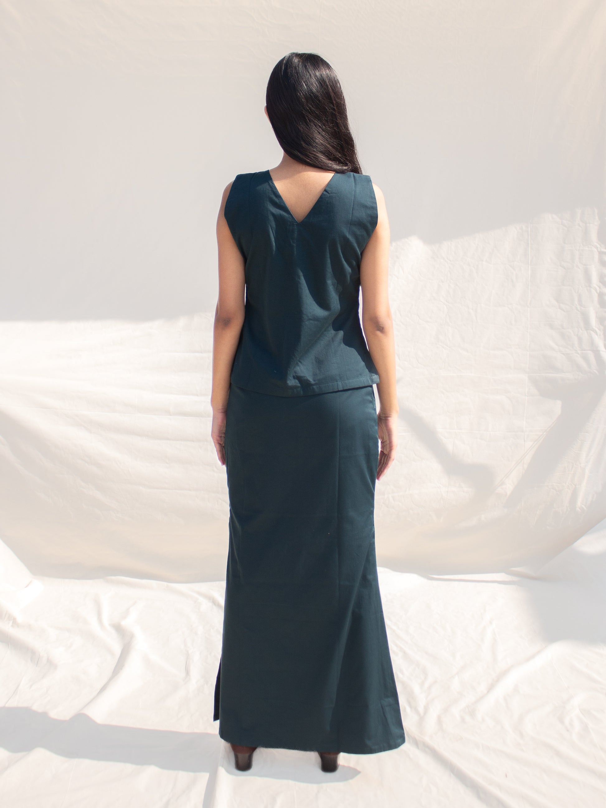 Woman wearing a dark green sleeveless dress against a white background
