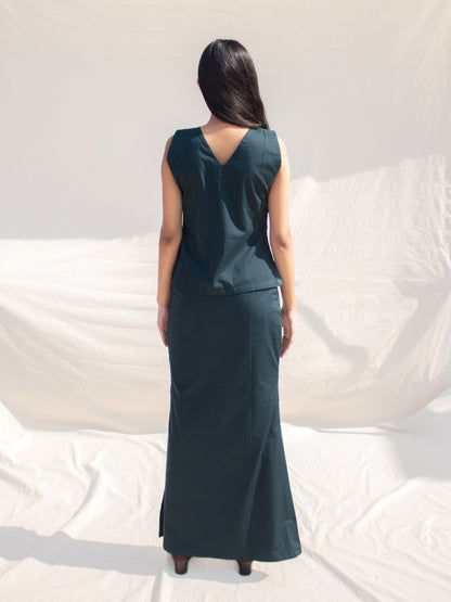 Woman wearing a dark green sleeveless dress against a white background