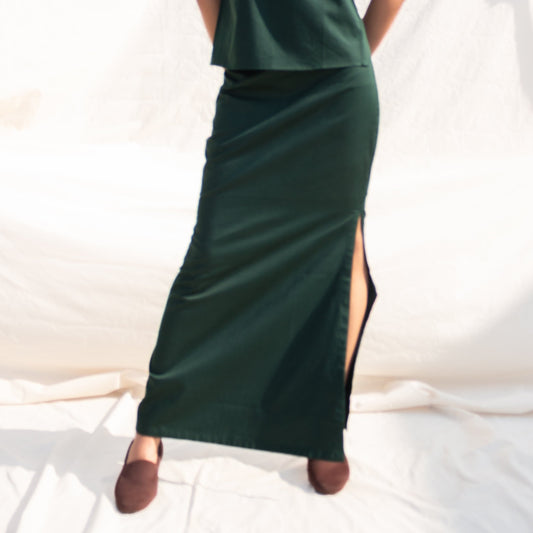 Woman wearing a green dress with a slit on a white background