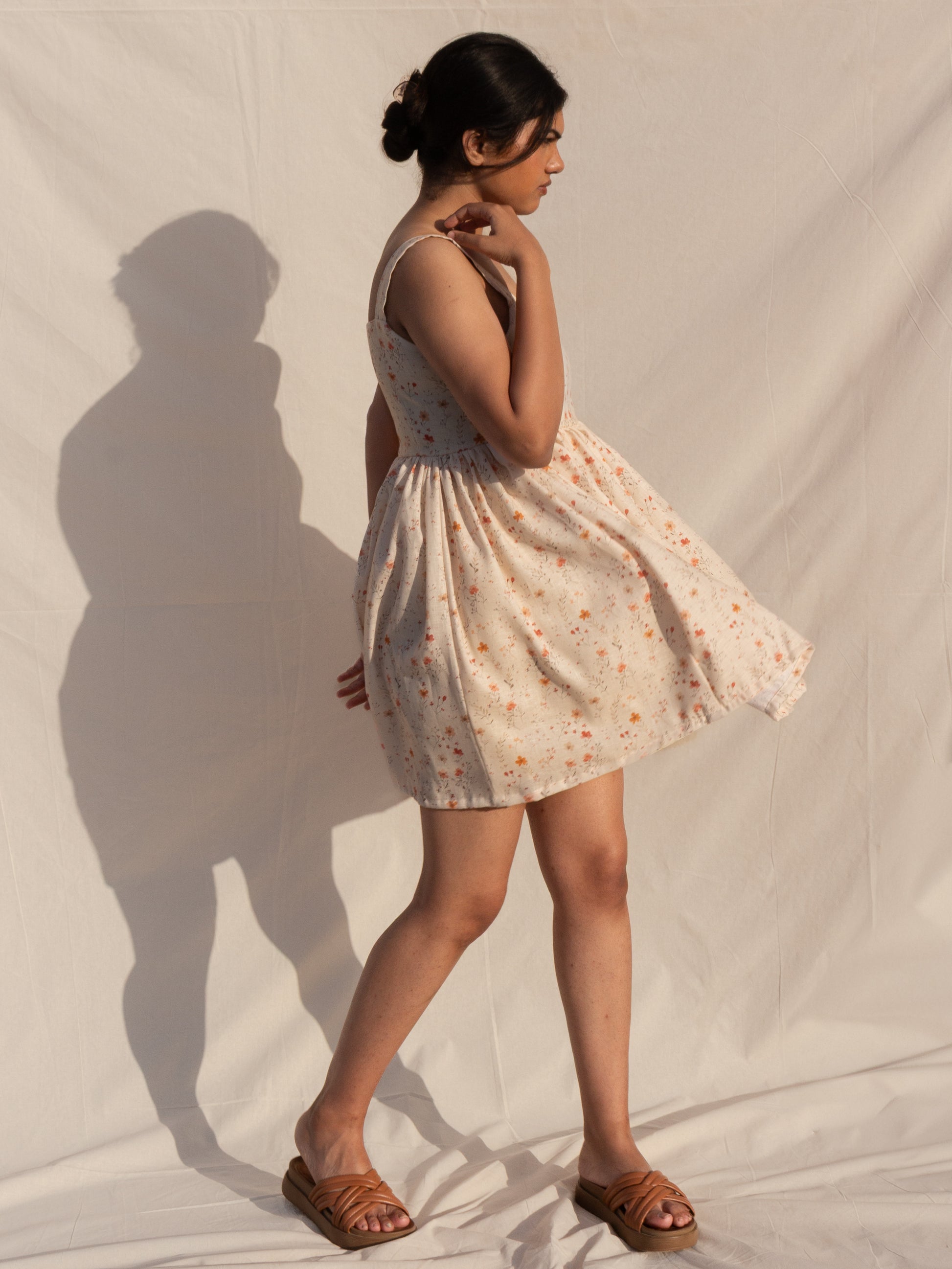 Woman in a floral dress standing against a plain background