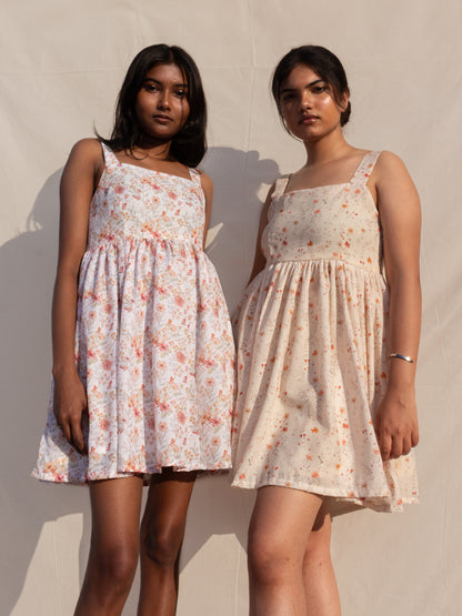 Two women wearing floral dresses against a plain background
