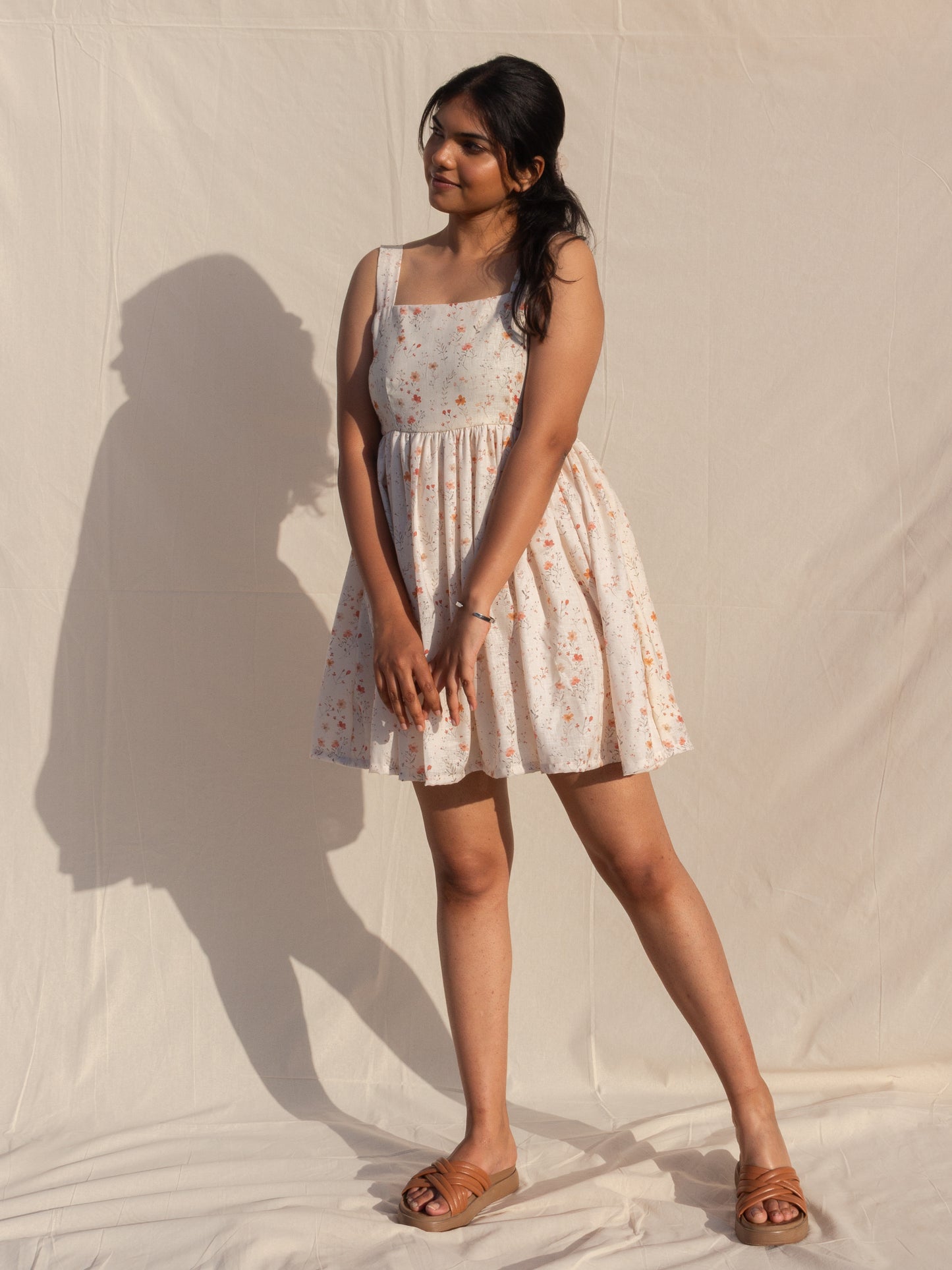 Woman wearing a floral dress standing against a plain background
