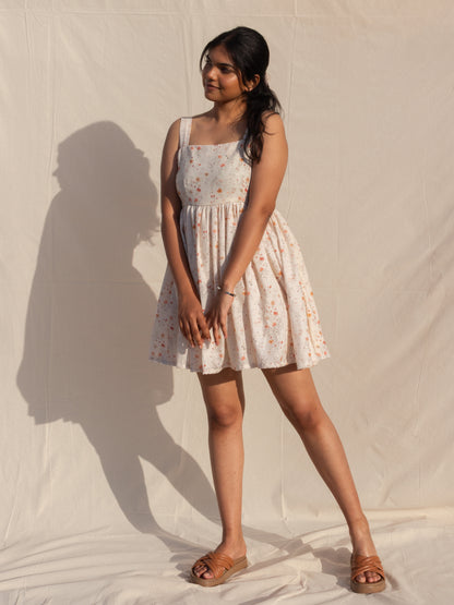 Woman wearing a floral dress standing against a plain background