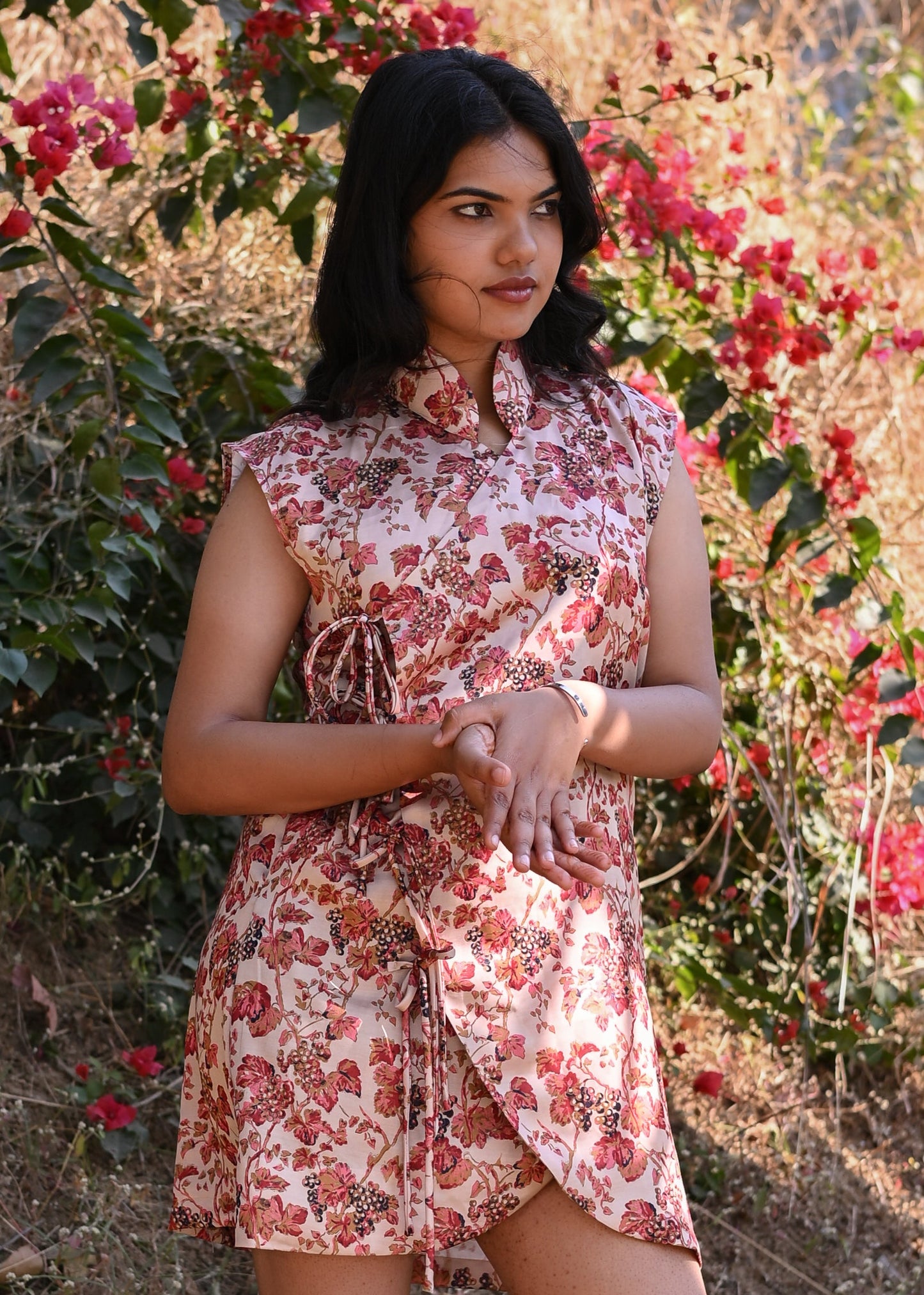 Woman in a floral dress standing in front of flowering bushes