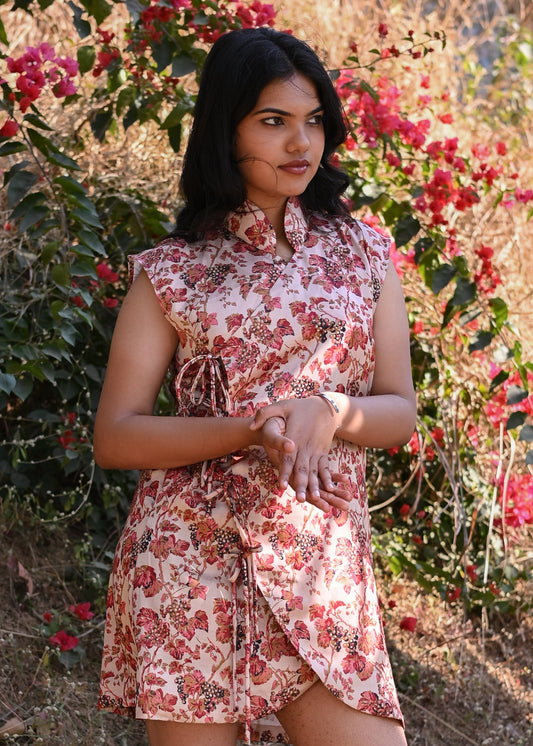 Woman in a floral dress standing in front of flowering bushes