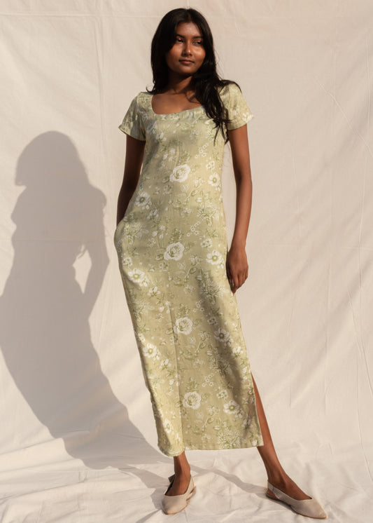 Woman wearing a light green floral dress against a white background