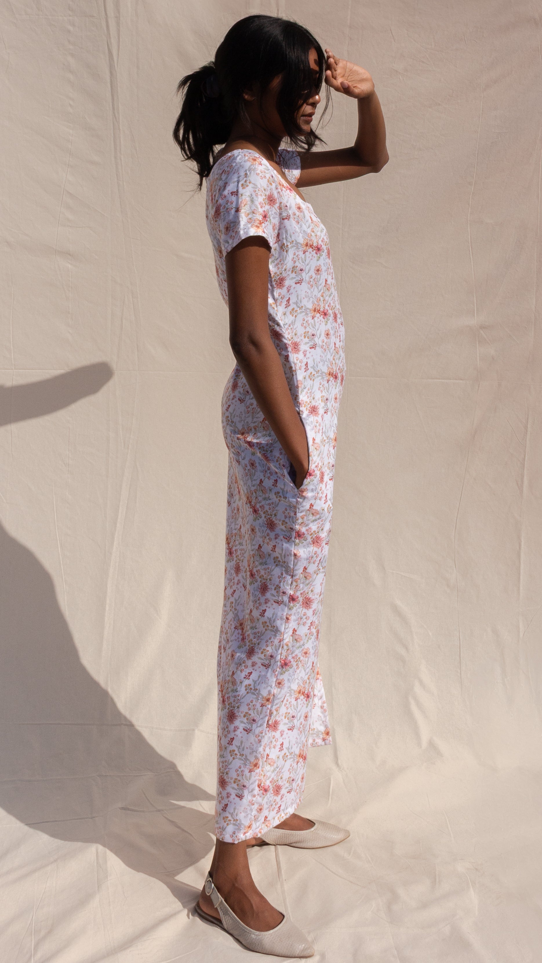 Woman wearing a floral dress standing against a plain background