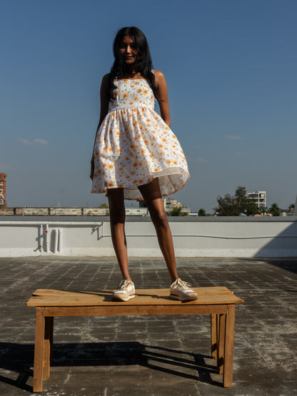 Woman in a floral dress standing on a wooden bench with a clear blue sky in the background