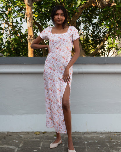 Woman in a floral dress standing outdoors with greenery in the background