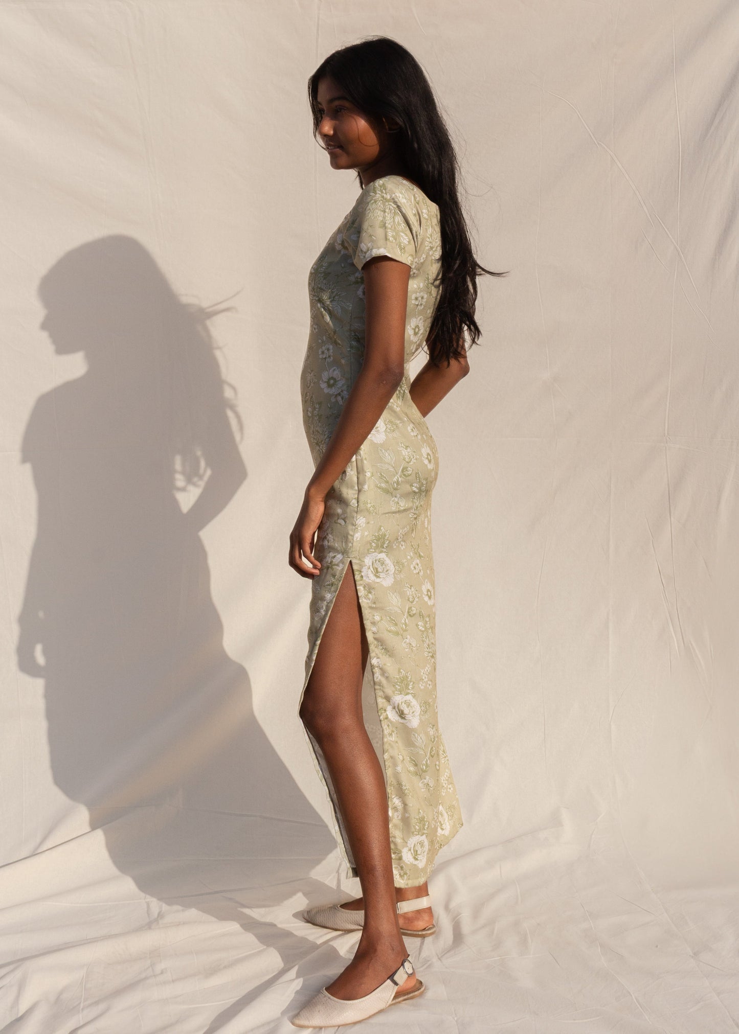 Woman wearing a patterned dress standing against a plain background