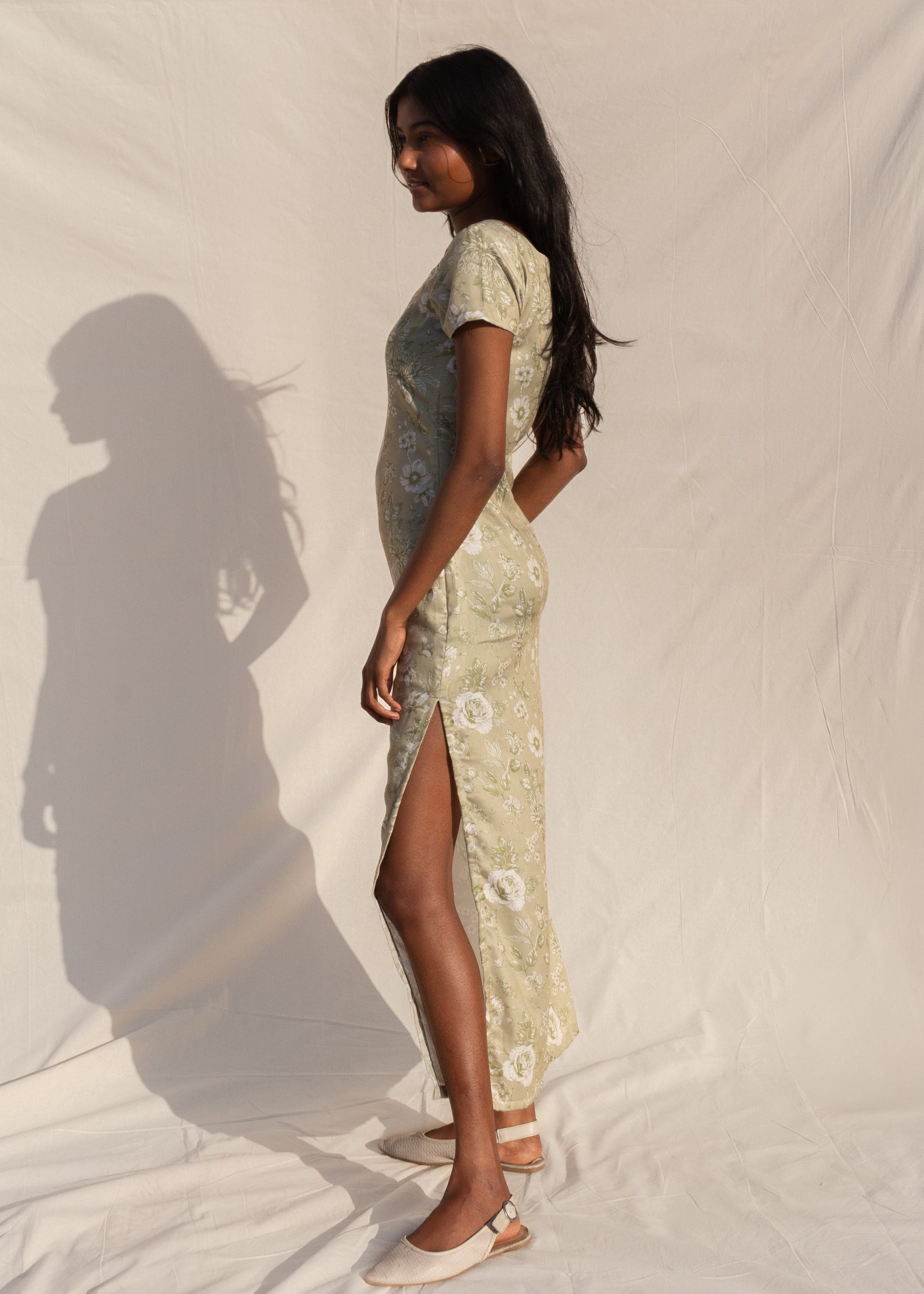 Woman wearing a patterned dress standing against a plain background