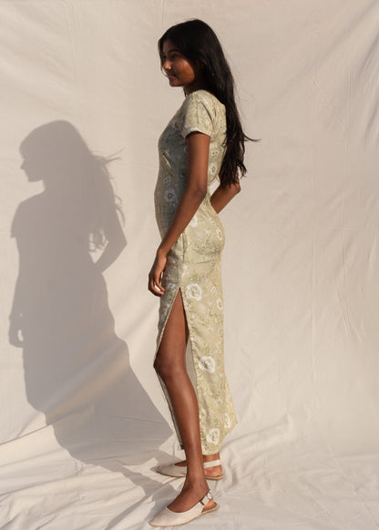 Woman wearing a patterned dress standing against a plain background