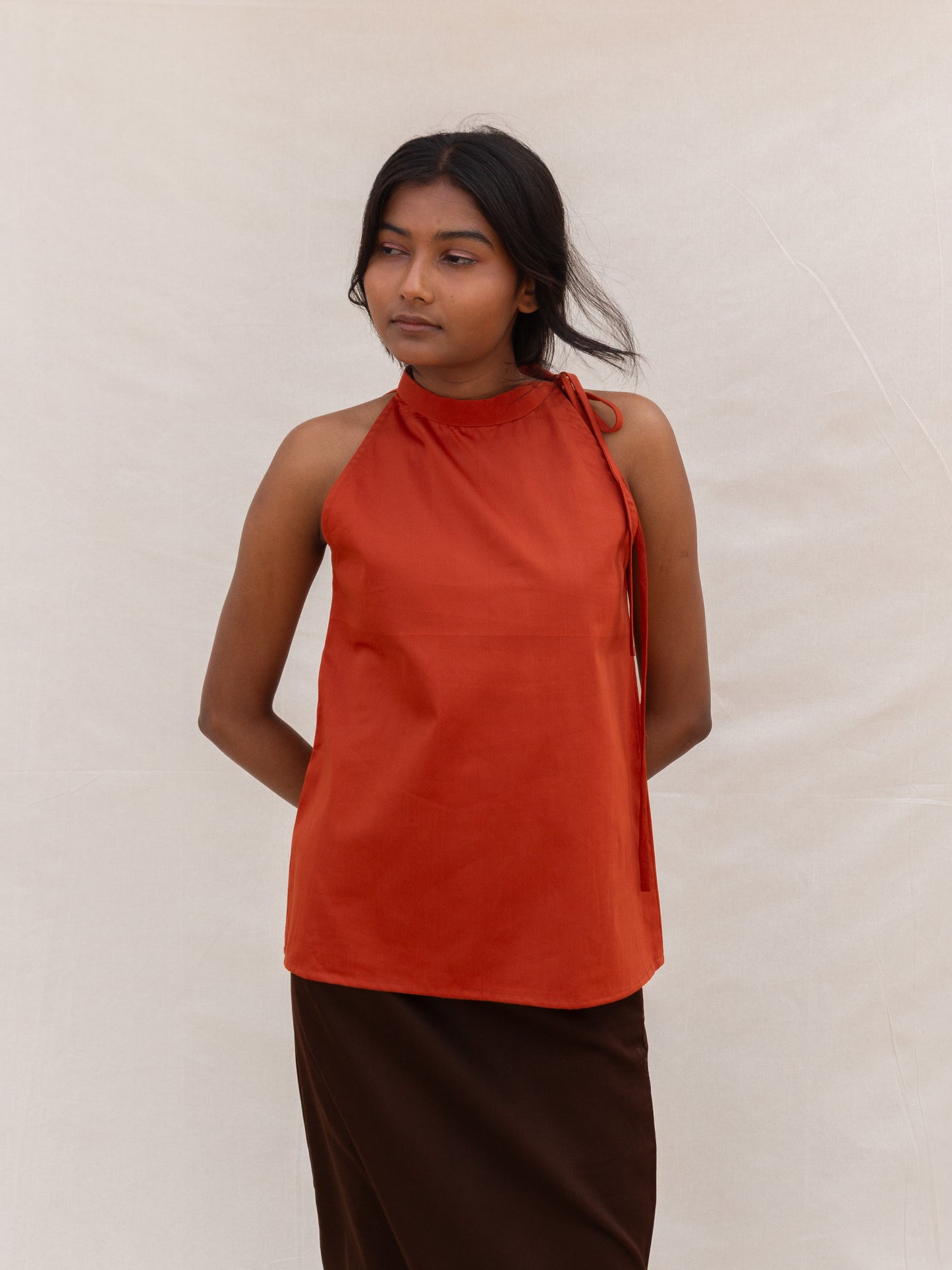 Woman wearing a rust-colored halter top against a plain background