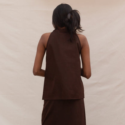 Woman wearing a brown sleeveless top and skirt set on a beige background